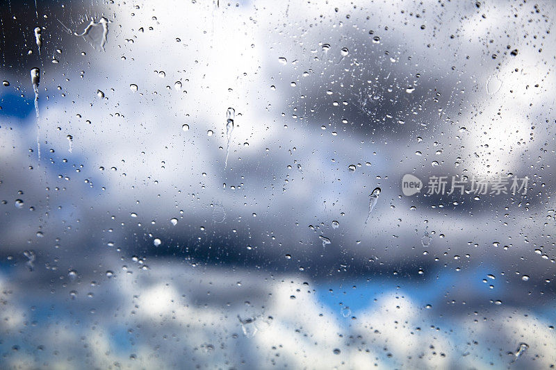雨点落在汽车挡风玻璃上，乌云密布