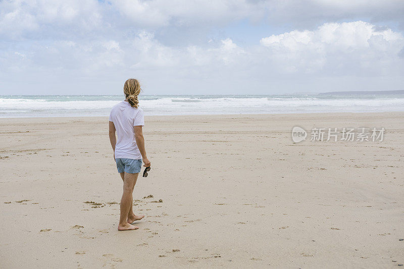 康沃尔纽基托万海滩上的男人，拿着太阳镜。