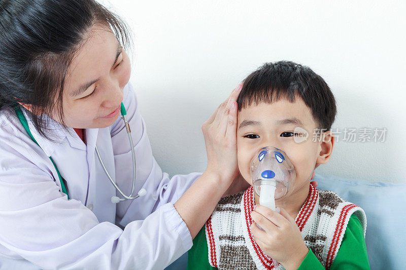 一名患有呼吸系统疾病的亚洲男孩在医生的帮助下使用吸入器。