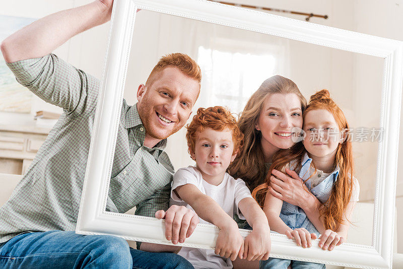 幸福的红发家庭透过白色的框架一起看，大的家庭肖像概念
