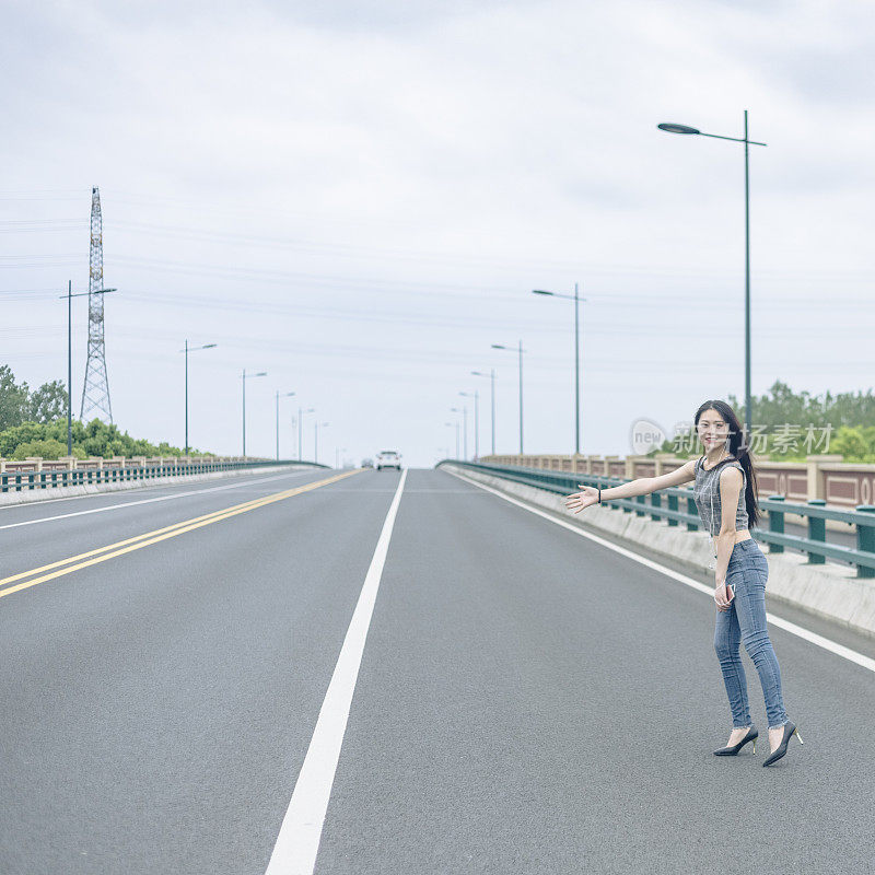 手持智能手机的女子在城市道路上招呼汽车