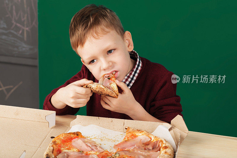 一个男生正在吃比萨饼当午餐。儿童不健康饮食观念。