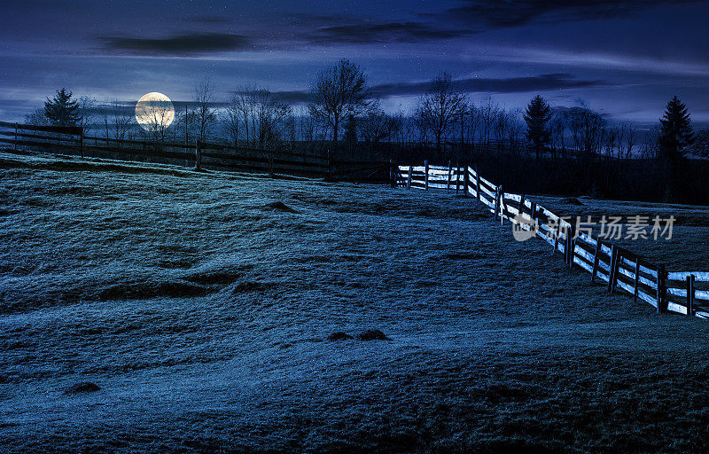 在秋天的夜晚，篱笆在长满草的山坡上