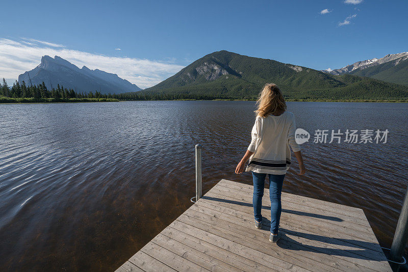 年轻女子在湖边码头凝望大自然