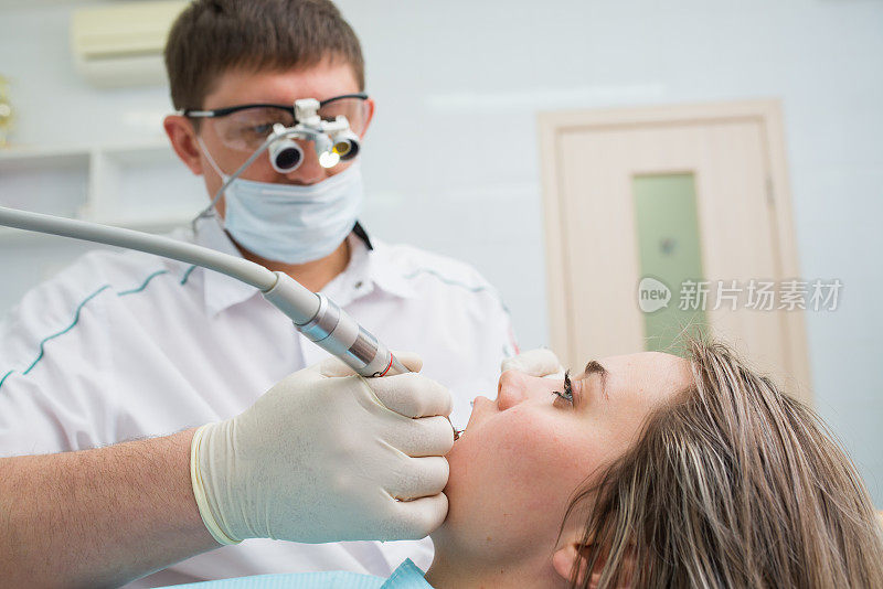 牙科医生治疗一个美丽的年轻女孩病人的牙齿。牙医接待处的那个女人。牙科医生治疗牙齿。