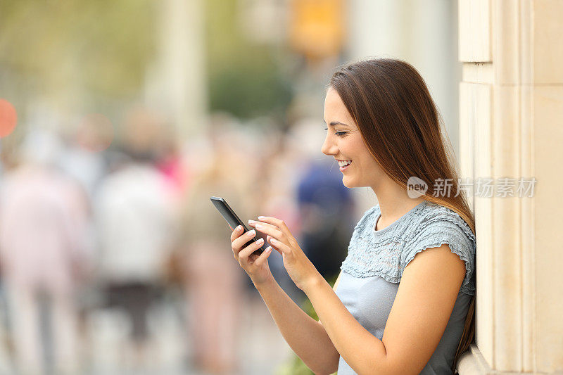 一个女孩在街上看智能手机的侧影