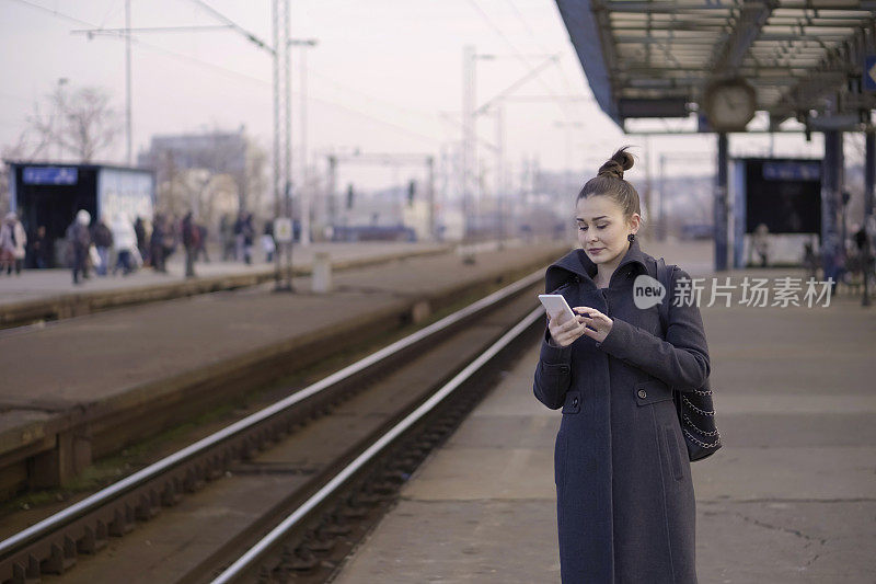 一个年轻女子在火车站用智能手机