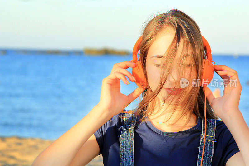 一个十几岁的女孩在海滩上听音乐