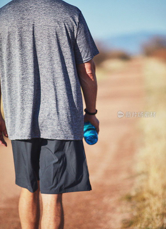 在阳光明媚的日子里，成年男性戴着健身追踪器在户外散步