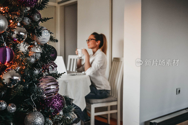 一个女人，有一台笔记本电脑，一棵圣诞树，喜欢喝咖啡