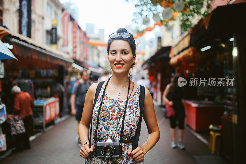 一个年轻的独自旅行者在新加坡街头市场的女人的肖像