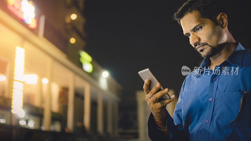 晚上在户外使用智能手机的中年商人。