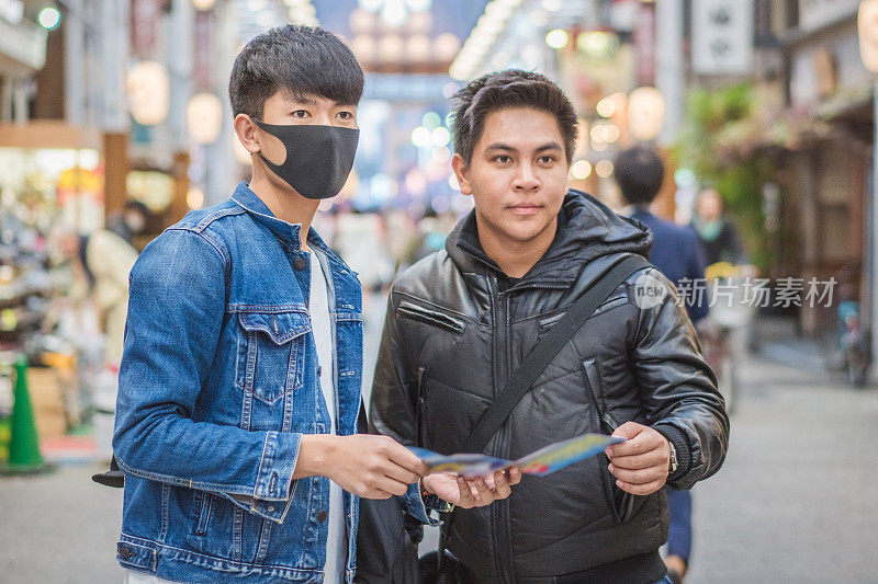 年轻的亚洲男子和日本朋友寻找旅游地点使用手机和花时间在亚洲旅行