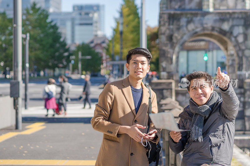 年轻的亚洲男子和日本朋友寻找旅游地点使用手机和花时间在亚洲旅行