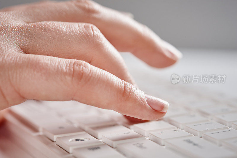 单身女性用手在白色电脑键盘上打字