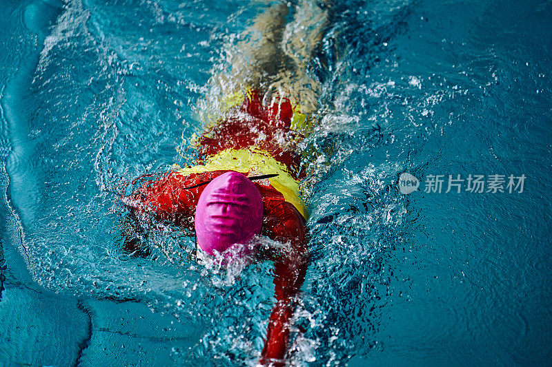女子游泳运动员以爬泳的方式游完全程。水花四溅向不同的方向。