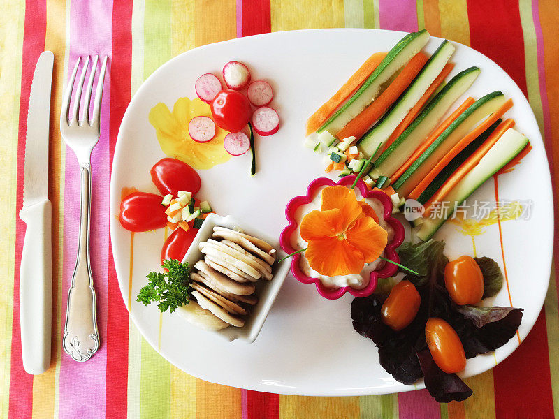 餐桌上的健康盘子，一块彩色桌布和几块新鲜切好的蔬菜，图片是用手机拍摄的