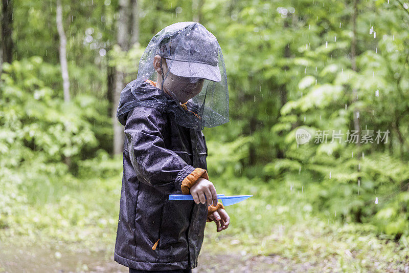 红发小男孩戴着蚊帐在露营地里玩耍