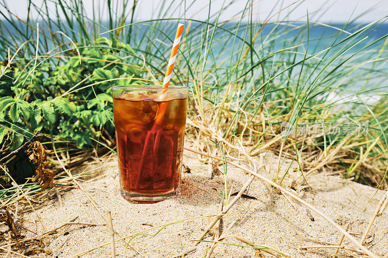 在一个炎热阳光明媚的夏日，在纽基菲斯特拉海滩的沙丘上喝一杯冰黑咖啡。