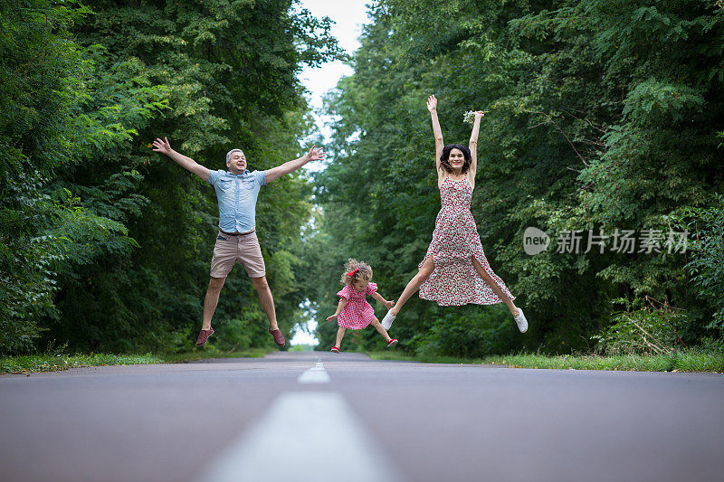 欢乐的一家人在乡间小路上跳跃。