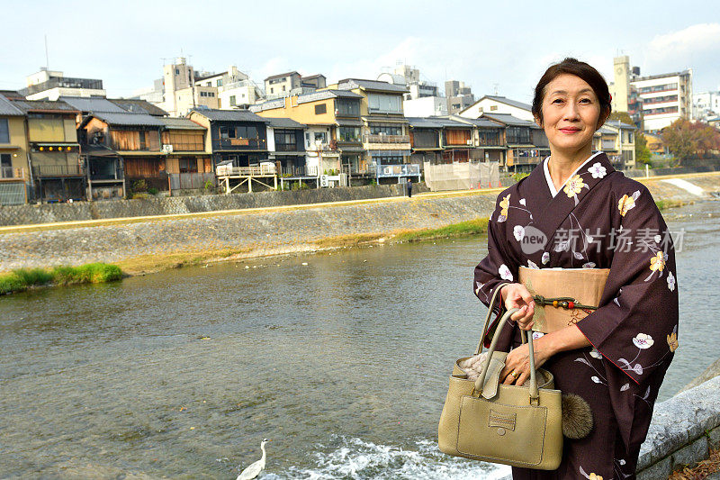 穿着和服的日本妇女沿着京都的加茂河行走