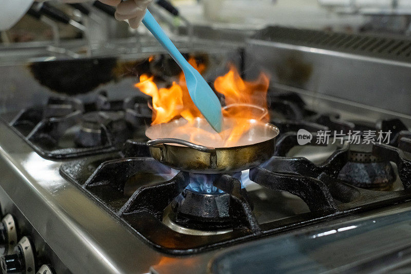 在厨房炉子上用煎锅用火焰烹饪