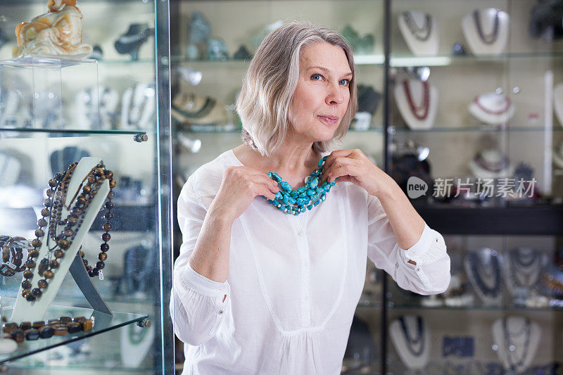 一位女士在一家珠宝店试绿松石项链和耳环