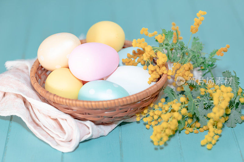 复活节彩蛋用不同颜色的含羞草枝装饰在桌子上