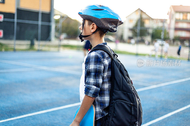 小学男孩在操场上玩滑板