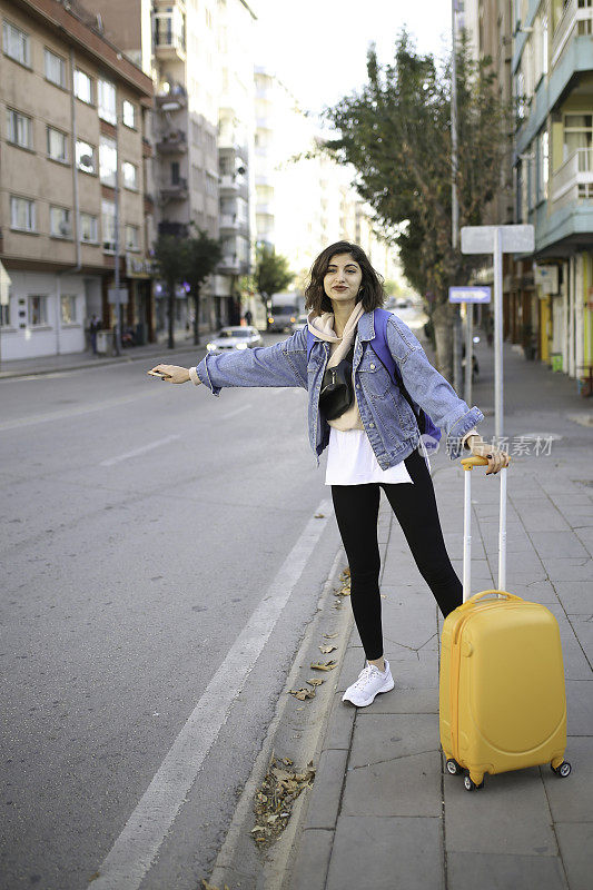 一个年轻女子在城里叫出租车。女人在外面等出租车。