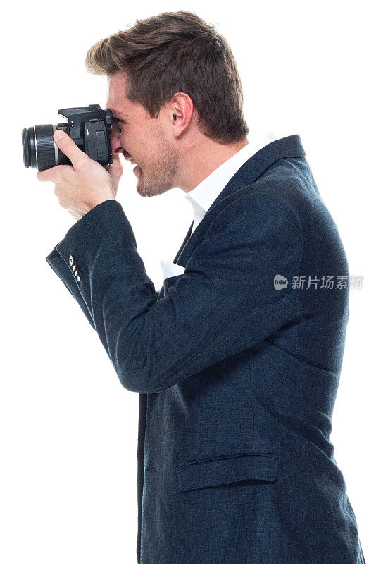 白人男性摄影师站着穿着纽扣衬衫和拿着相机