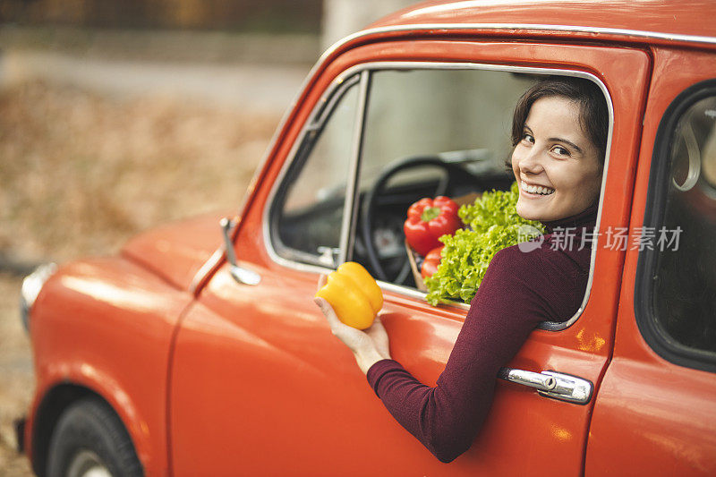 女人开着车，拎着购物袋