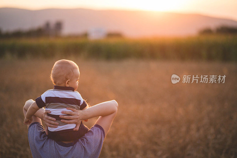 女人抱着孩子在金黄的麦穗地里种庄稼。