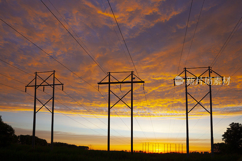 色彩斑斓的黎明天空和剪影般的电力塔和电线。
