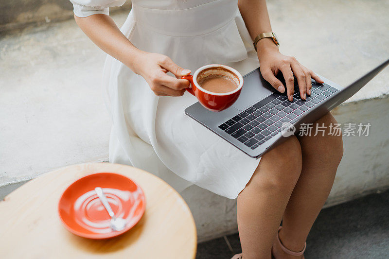 年轻的亚洲女人在咖啡馆使用笔记本电脑