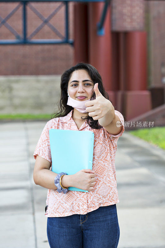 一名尼泊尔学生拉下口罩，竖起大拇指示意返校