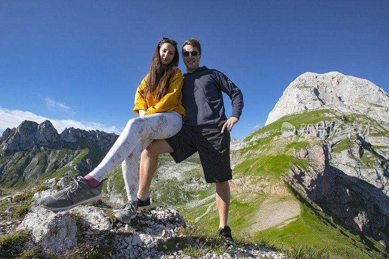 微笑的年轻夫妇在山中徒步旅行休息