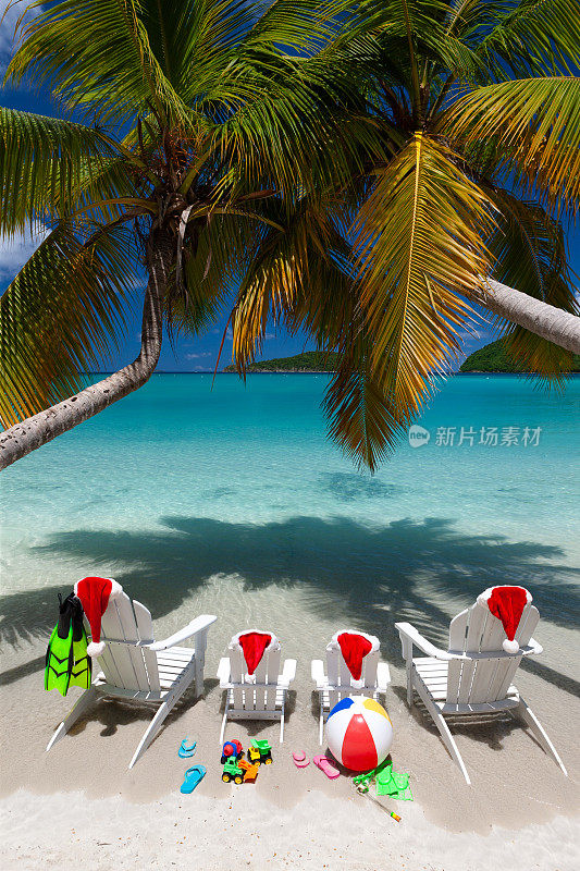 热带海滩上的阿迪朗达克椅子和带圣诞帽的棕榈树