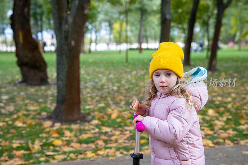小女孩在公园里骑踏板车。