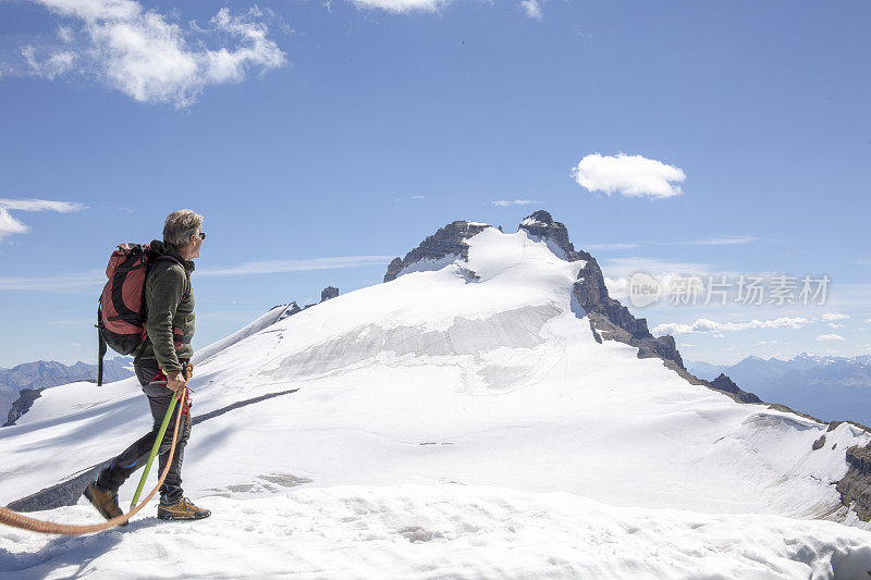 一位男性登山运动员到达了雪山的顶峰