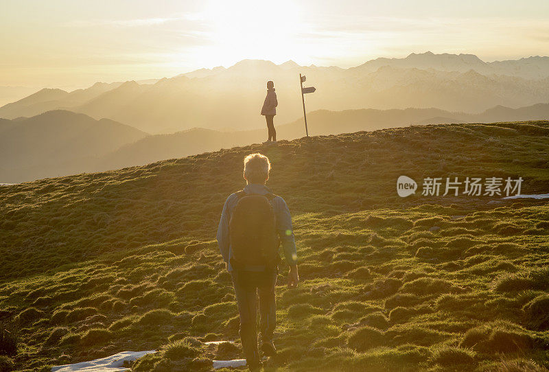 夫妇走在高高的草地上，路标