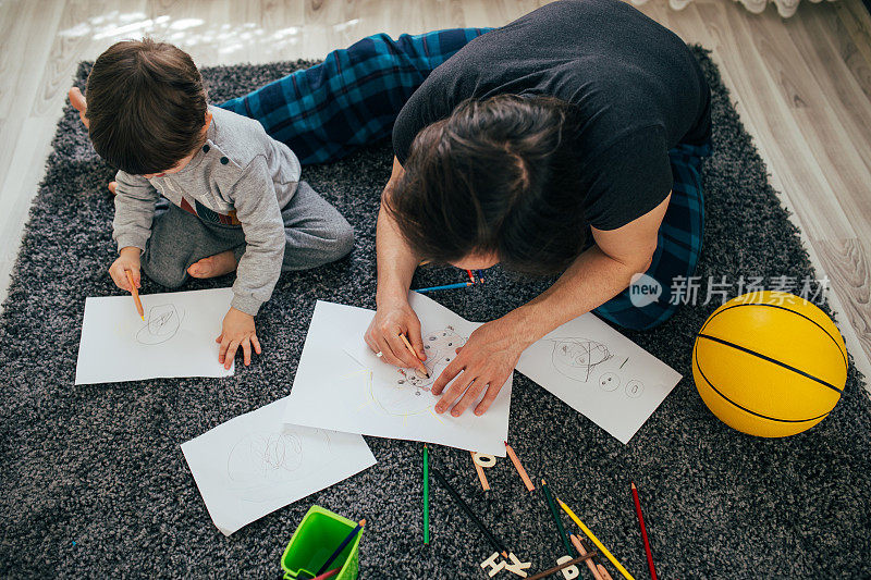 爸爸和蹒跚学步的儿子用彩色铅笔画画