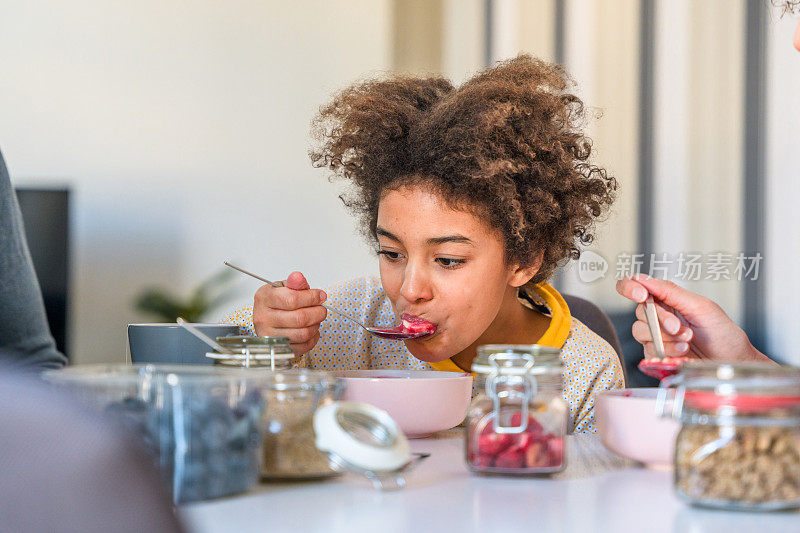 可爱的青少年混血女孩在家吃冰沙碗