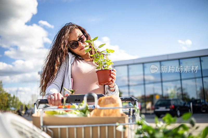 一位漂亮的年轻女子在超市买完东西，买了一些蔬菜和漂亮的花。