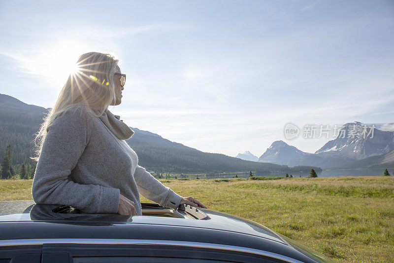 女人从汽车的天窗中站起来，望向窗外