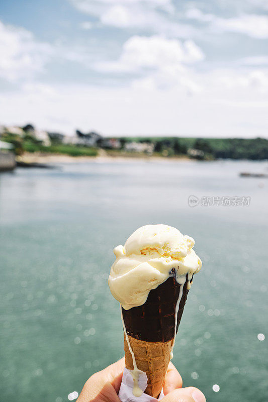 6月的一个阳光明媚的日子，康沃尔的圣莫斯，在水边手里拿着一个冰淇淋蛋筒。