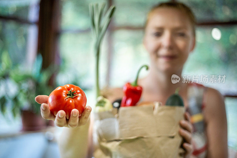 一个红头发的年轻女人站在厨房里，手里拿着蔬菜