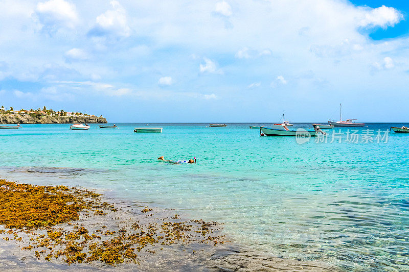 风景优美的加勒比岛屿，curaçao碧蓝的海洋和广阔的天空，港口里有船，海湾里有浮潜者