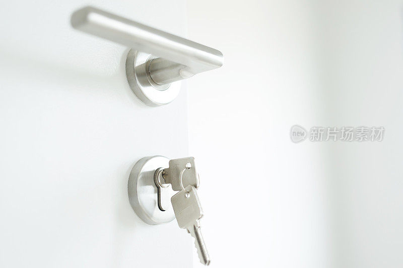 房子钥匙在家里形状的钥匙扣银钥匙环锁在一扇门。概念购买房地产代理房屋和公寓。