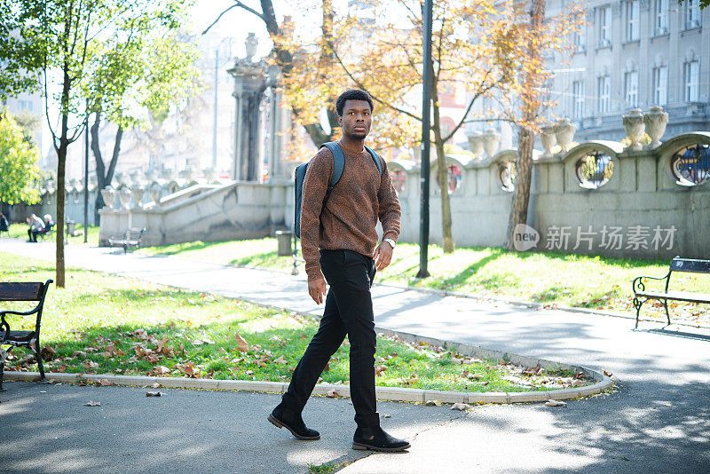 一个年轻的非裔美国人走过公园的画像